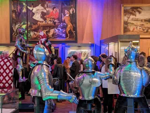 The Armoury at Fitzwilliam Museum with dramatic colorful uplighting for corporate networking events.