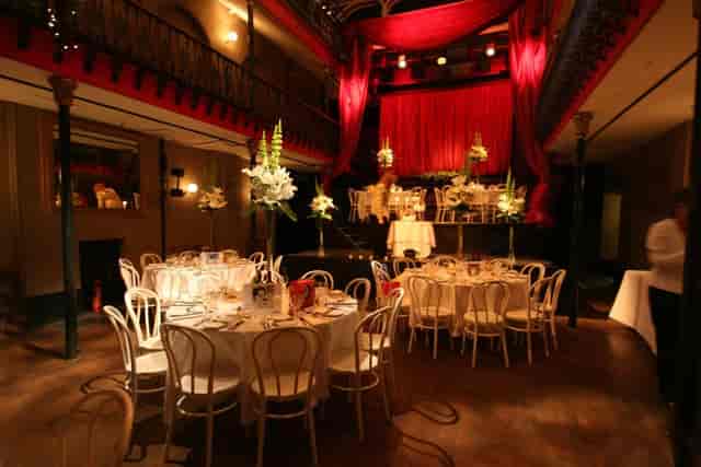 Hoxton Hall Main Hall with red stage drapery for gala dinner and exclusive evening reception.