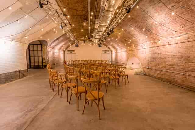Versatile event space in Kachette with exposed brick and string lighting for gatherings.
