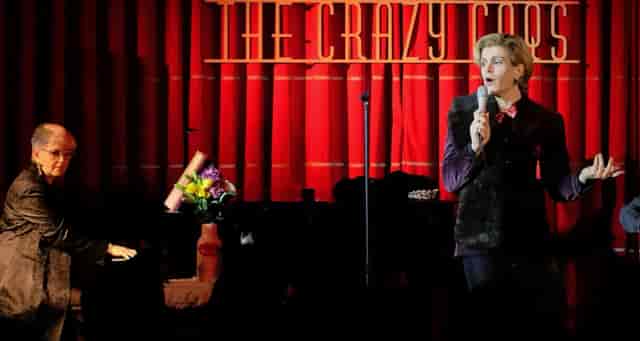Cabaret duo performing on stage at Crazy Coqs with red curtains. Live music event venue.