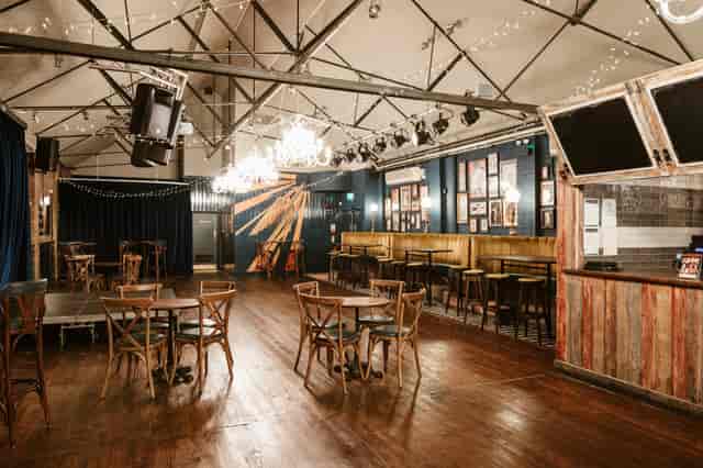 Rustic-industrial Boston Room event space with stage lighting for networking and live performances.