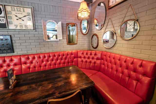 Cozy red tufted seating in The Larwood & Voce, ideal for informal team meetings.