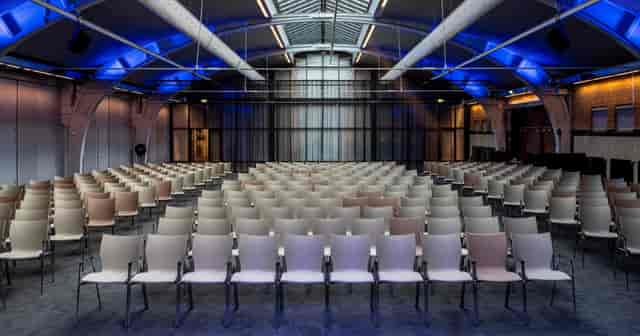 Industrial-chic theater venue, Limousin 1, with blue lighting for modern corporate event setup.