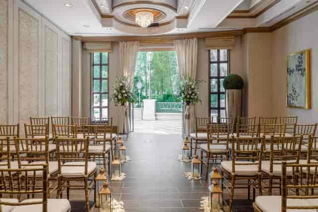 Gold chiavari chairs and floral pedestals in an elegant event space for weddings and corporate galas.
