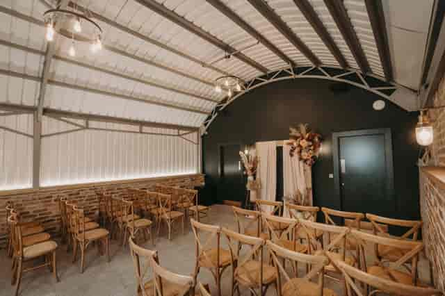 Industrial-chic ceremony space at The Old Workshop, Lodge Farm featuring exposed brick walls.