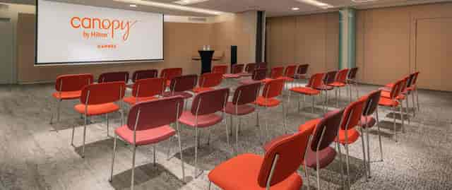 Theater-style meeting room with vibrant seating at Canopy by Hilton Cannes for corporate events.