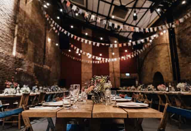 Industrial-chic private event space with bistro lighting for rustic weddings and corporate socials.