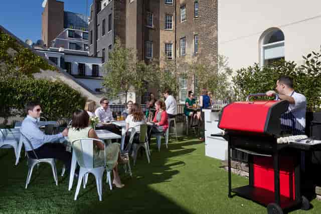 Outdoor networking event at Ann Rylands & Terrace with green turf and grill setup.