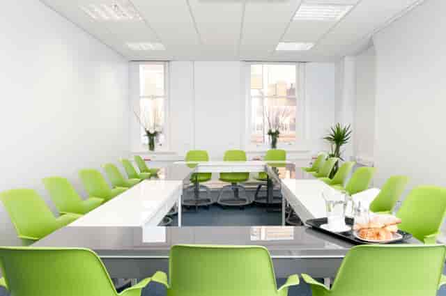 Modern meeting room with U-shaped layout and green chairs for workshops in Sydney.
