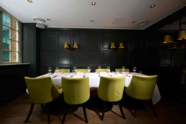 Stylish dining space with green chairs for corporate events and networking lunches.