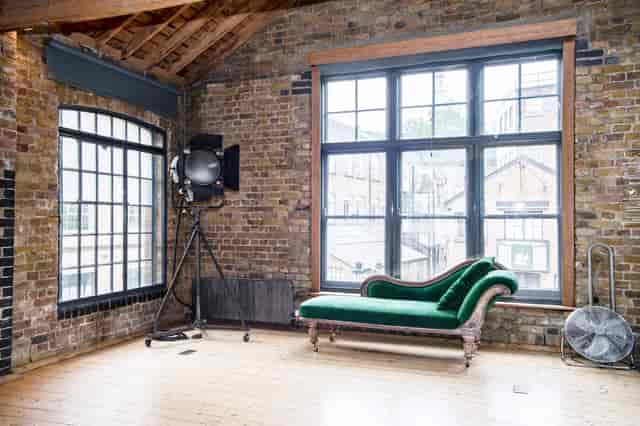 Stylish industrial event space with exposed brick and elegant green chaise lounge.