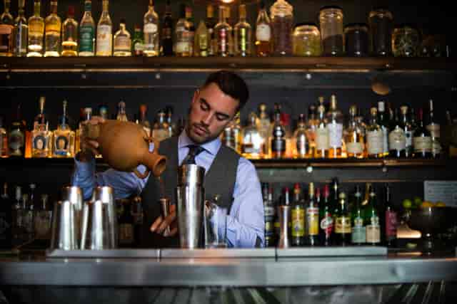 Bartender crafting cocktails at upscale Looking Glass Cocktail Club venue for events.