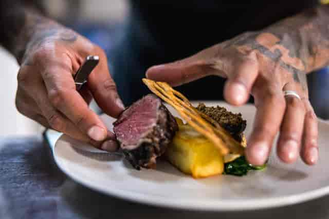 Chef plating gourmet dish at The Queen Charlotte for upscale culinary events.