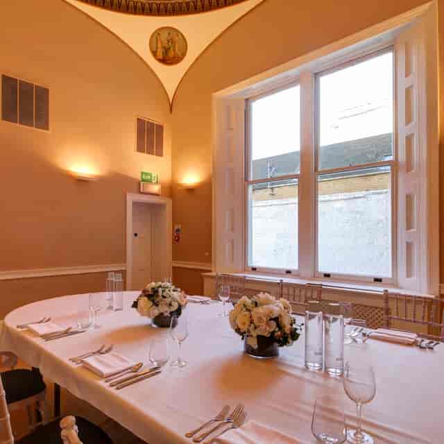 Elegant meeting room with round table, floral centerpieces for corporate events.