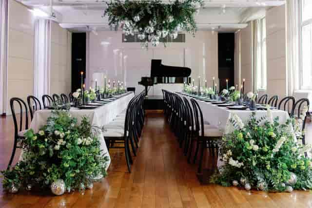 Elegant event space in Princess Alexandra Hall with floral centerpieces and grand piano.