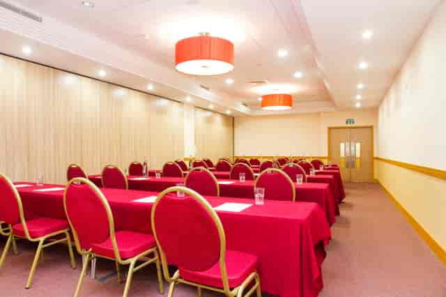 Pimlico 1 classroom setup with red linens for corporate workshops and training sessions.