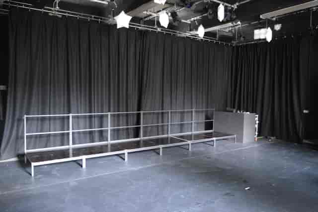 Versatile event space with minimalist stage and elegant black curtains at Little Angel Studios.