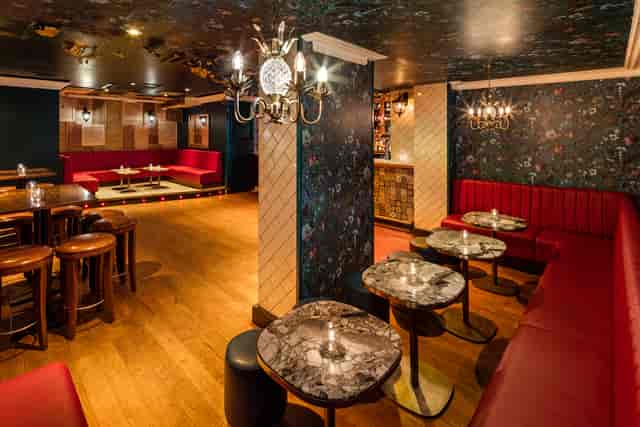 Stylish event space in Shoreditch with plush red seating and elegant marble tables.
