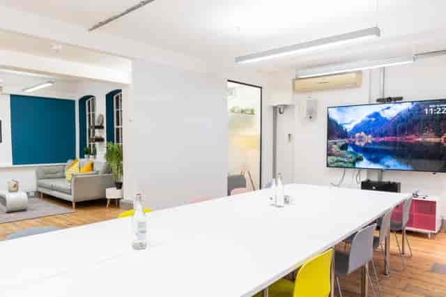 Modern meeting space with large white table and colorful chairs for collaboration events.