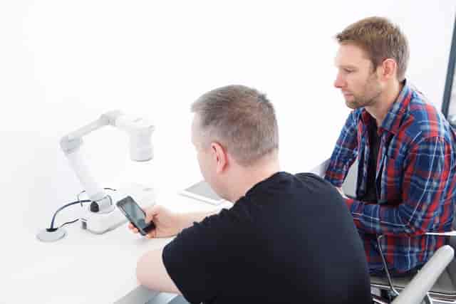 Professionals collaborating in The Basement, Sutherland Labs, with modern tech for presentations.