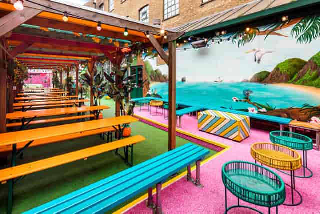 Vibrant outdoor event space in Shoreditch with colorful benches and tropical decor.