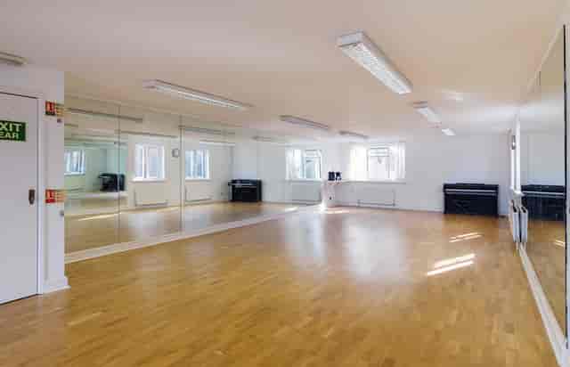 Versatile event space with polished wooden floor and large mirrors for workshops and dance classes.