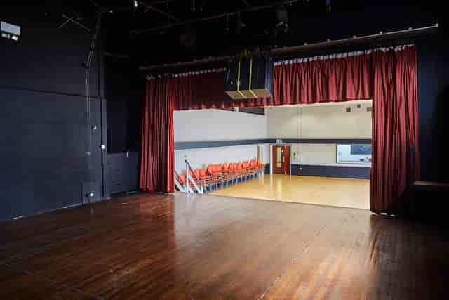Main Hall at Mill Co. Rose Lipman with stage and red curtains for events and presentations.